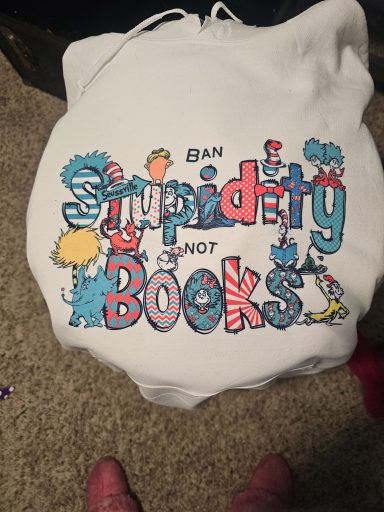 White tote bag with colorful text: "Ban Stupidity, Not Books!"