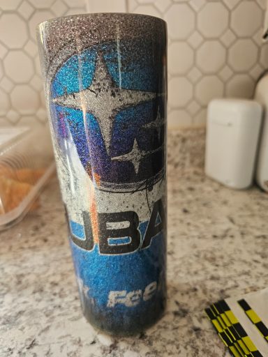 A blue and black insulated tumbler with a Subaru logo and graphic design.