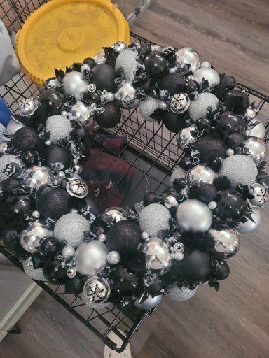 Black, silver, and white ornament wreath with various round decorations.