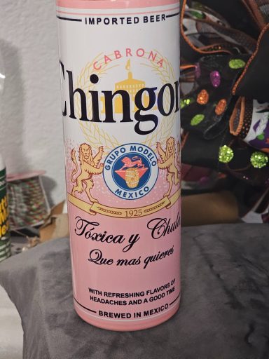 Pink canister labeled "Chingón" with a decorative crest and text in Spanish.