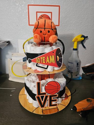 Three-tiered cake themed with basketball decorations and 'LOVE' on the bottom tier.